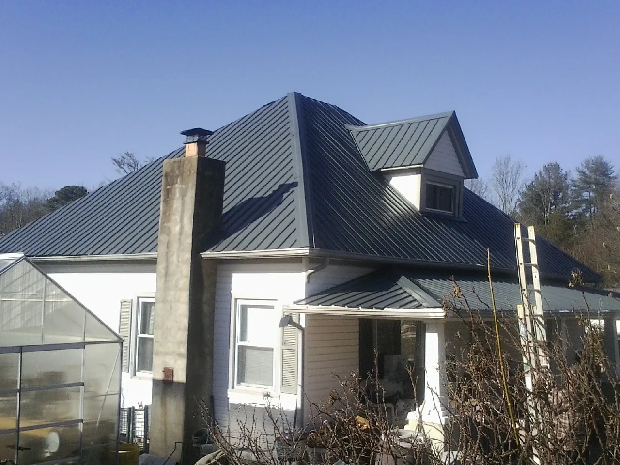 Dark blue standing seam metal roof on a white farmhouse with dormer — Slate & Tile Roof Repair by Roofing Brothers in Tallapoosa