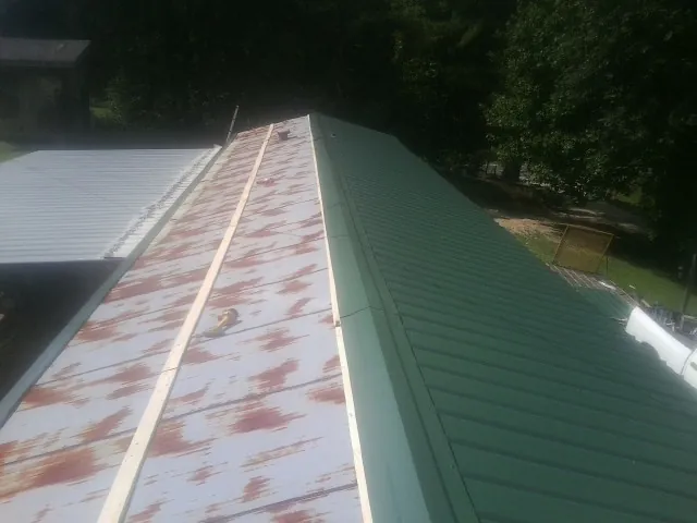 Old rusted panels beside newly installed green metal roofing — Wind Damage Roof Repair by Roofing Brothers in Tallapoosa