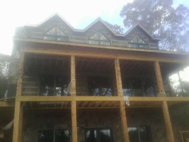 Dormers and porch framing on a large log home under construction — Roof Coating work by our crew in Tallapoosa