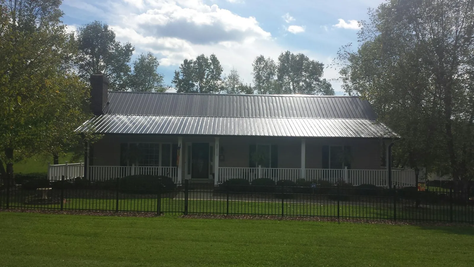 Gray metal roof on a brick ranch with a full width front porch — Gutter Guard Installation work by our crew in Tallapoosa