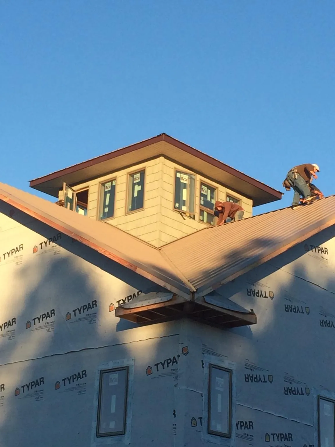Roofers working around a rooftop cupola on a new metal roof at sunset — Roof Waterproofing in Tallapoosa by Roofing Brothers